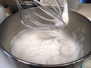 Smooth, glossy meringue in a steel mixer, forming perfect peaks on the whisk.